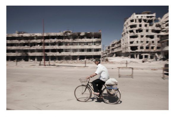 Un hombre pasea en bicicleta rodeado de ruinas. Foto: Carole Alfarah (EFTI).