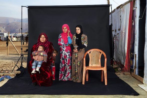 Gente, Tercer Premio, fotografías individuales Dario Mitidieri, Italia, CAFOD, Retratos de familias perdidas 15 de diciembre de 2015. Una familia siria posa en el campo de refugiados Beqaa Valley junto a una silla que representa a un miembro de su familia desaparecido. Según ACNUR, a finales de 2015, más de 370,000 refugiados sirios viven en el campo Beqaa Valley, cerca de la frontera Siria.. 