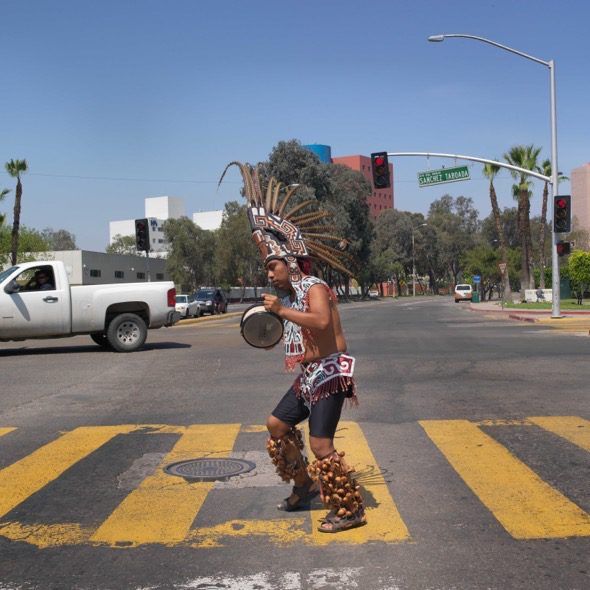 Un mejicano cruza un paso de peatones realizando una danza tradicional en Tijuana, México.