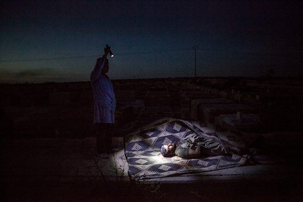 Un rebelde sirio ilumina el cadáver de un combatiente rebelde durante su entierro en Alepo, Siria, 2012. Foto: Manu Brabo.