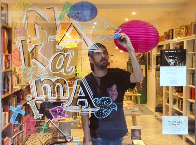 El artista Borja Robles decora el escaparate de la librería Nakama en Madrid.