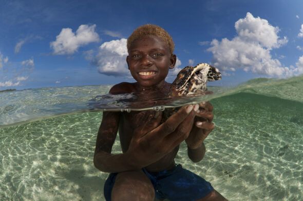 Un chico con una tortuga carey en Papua. Foto: Jurgen Freund. 