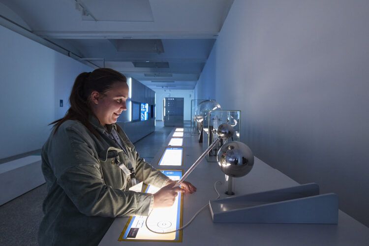 Una visitante interactúa con la electricidad en la exposición 'Conectados al futuro: la transición energética' de Redeia.