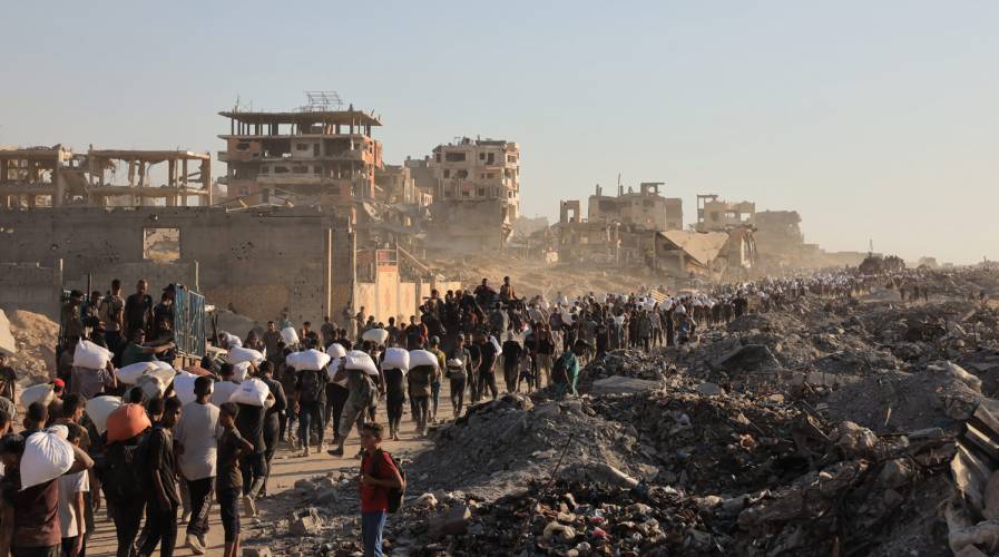 Ciudadanos de Gaza portan sacos de harina que les racionan los genocidas sionistas para provocar el exterminio por hambruna. Foto: UNRWA.